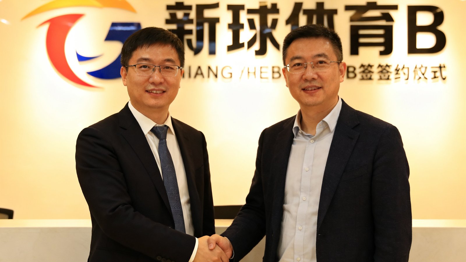 新球体育B轮融资签约仪式现场，创始人与投资方代表握手合影，背景是公司logo墙